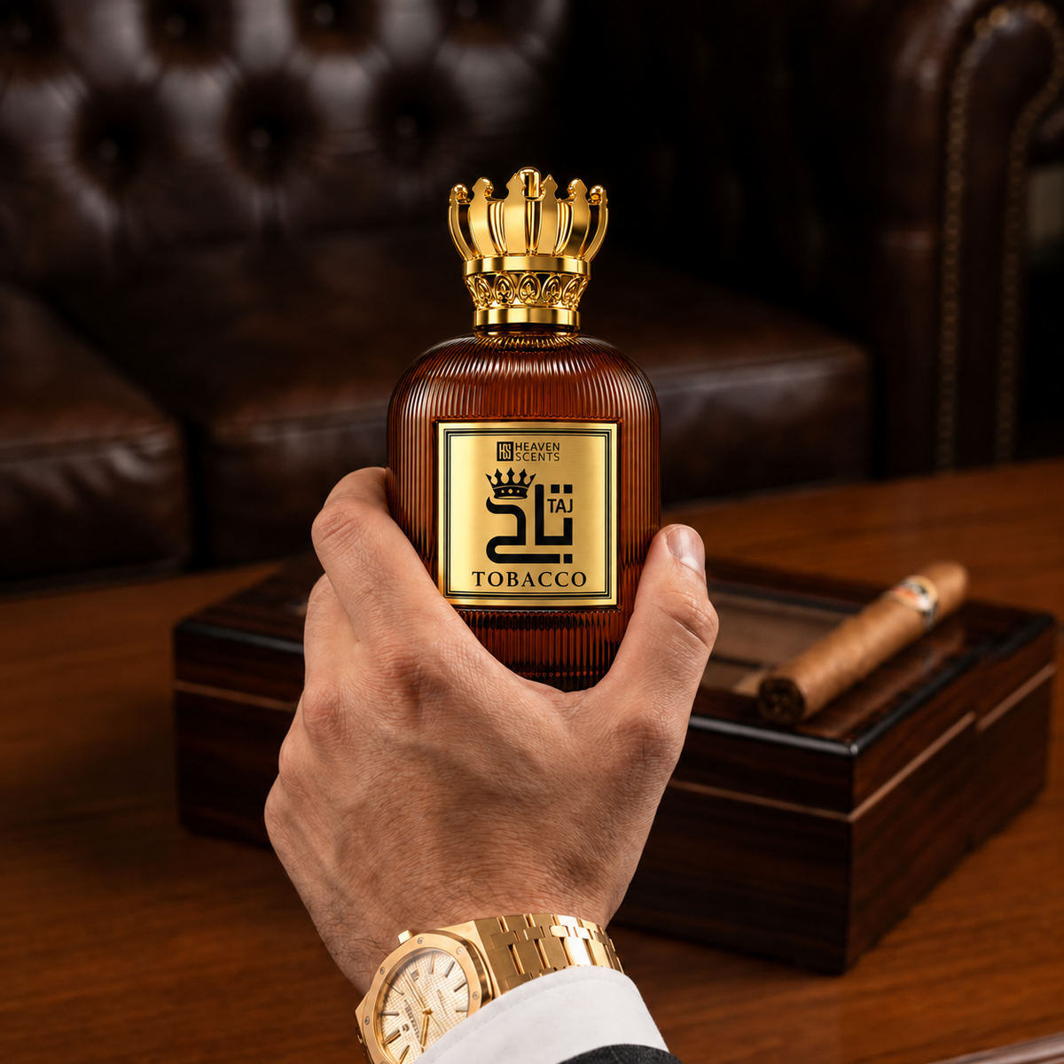 Taj Tobacco Perfume 100ml with its open gold crown cap, held above a wooden desk